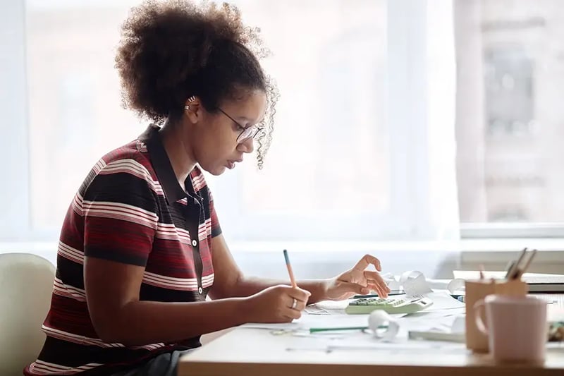 Woman at desk with a pencil and calculator.