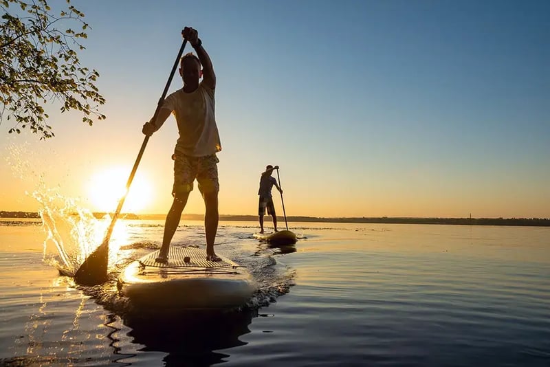Two men paddleboarding at sunrise.