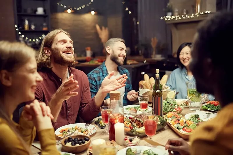 Group of people laughing and talking around a dinner table.