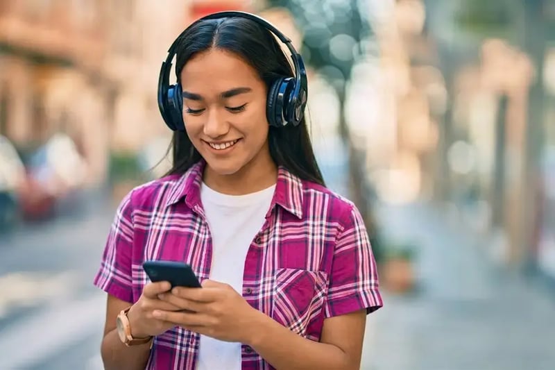 Woman with headphones on looking at cell phone.