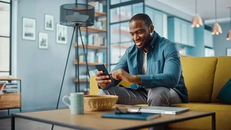 Man on sofa looking at a cell phone.