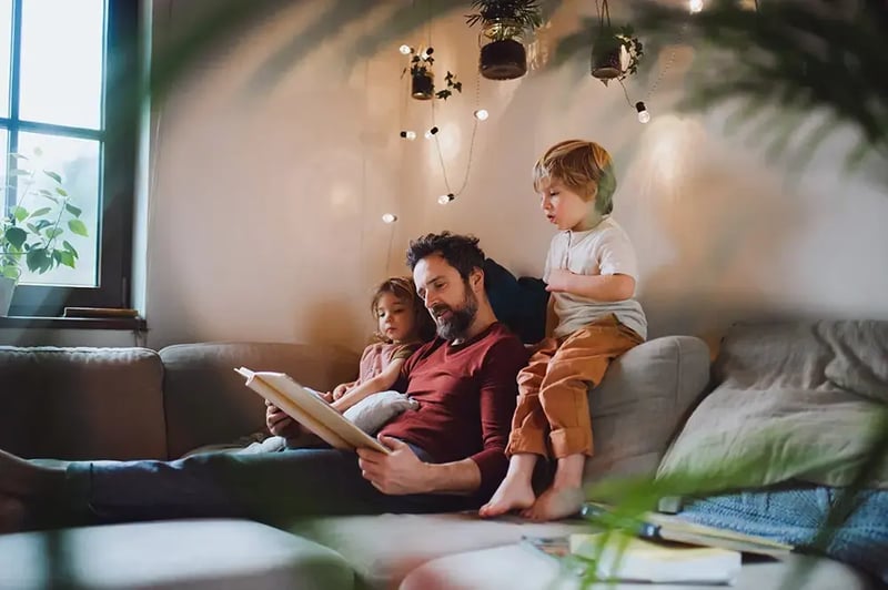 Father reading to two children on a sofa.