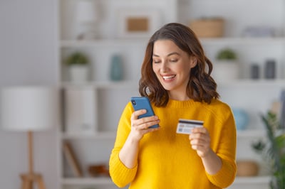 Woman on a cell phone holding a credit card.
