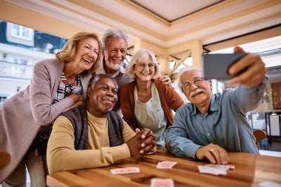 Group of seniors taking a selfie at a card table.