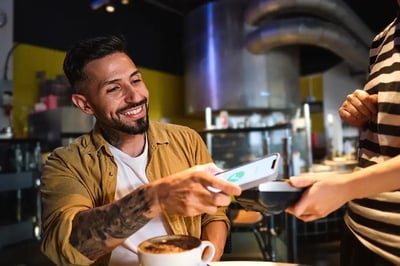 Man paying for coffee using a digital device.