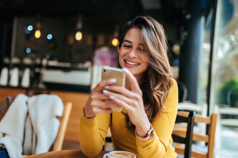 Woman at cafe looking at a cell phone.