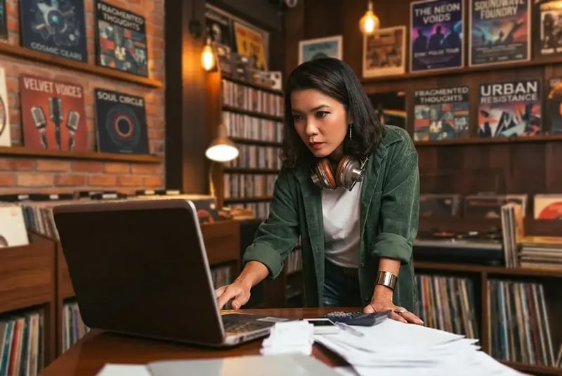 Woman on laptop in a record store.