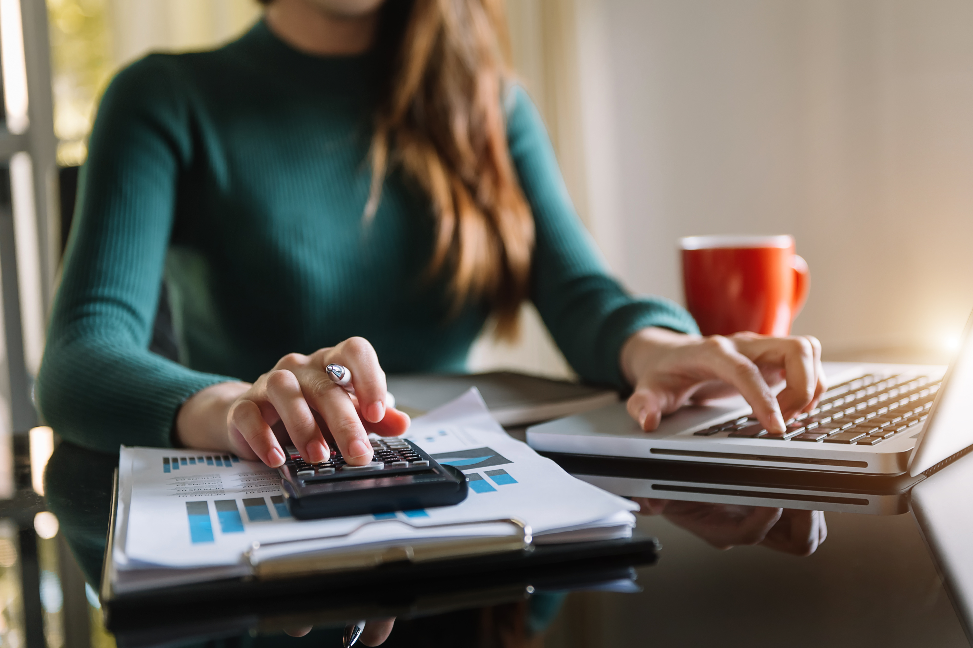 Woman working on a desktop calculator.