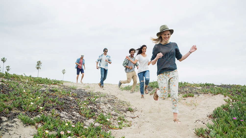 A group of five friends running on the beach