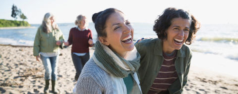 four-women-walking-smiling-on-beach