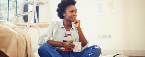 Photo of a person sitting cross legged on the ground holding a cup