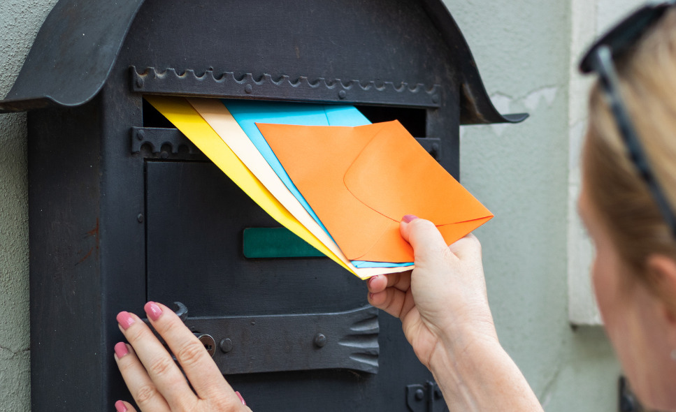 hand putting colorful envelopes into a locked mailbox