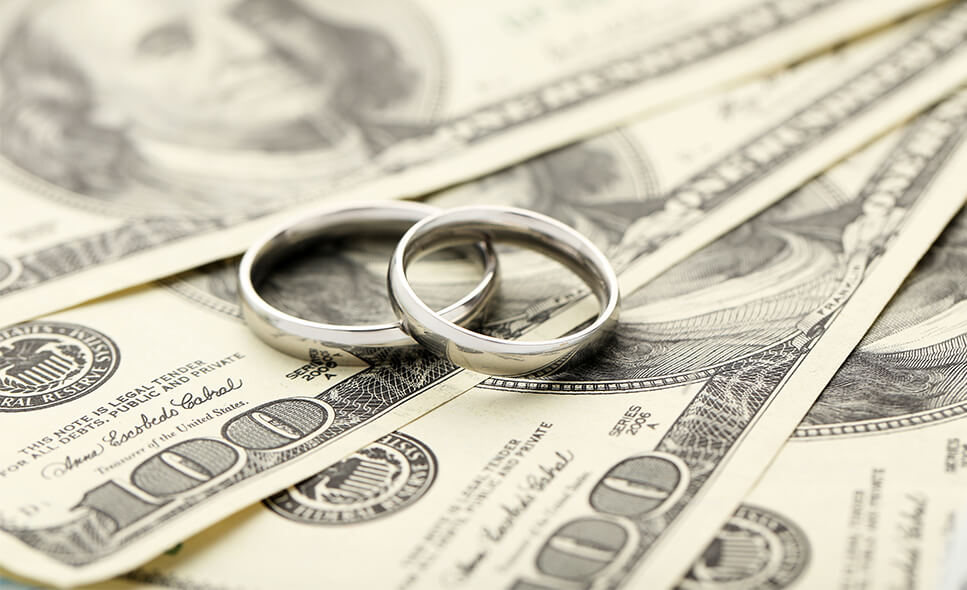 Closeup of two wedding bands on top of a stack of money