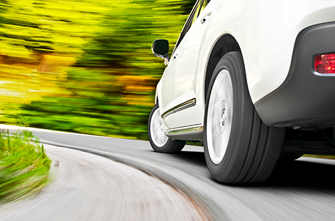 Closeup image of a car's rear tires as it races down a road