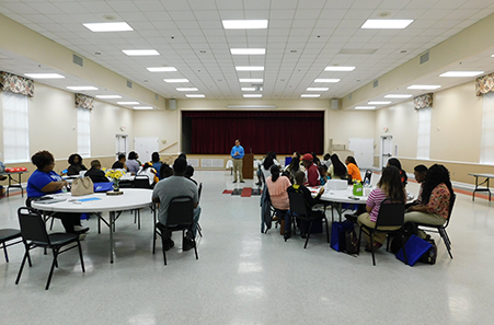 Photo of people sitting at tables as they listen to a speaker in a professional setting