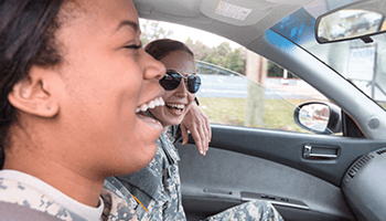 Two military members laughing inside a car