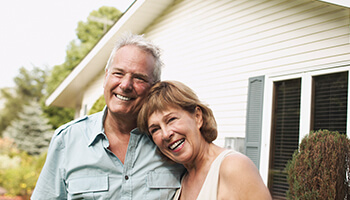 Image of couple smiling in front of their purchased home