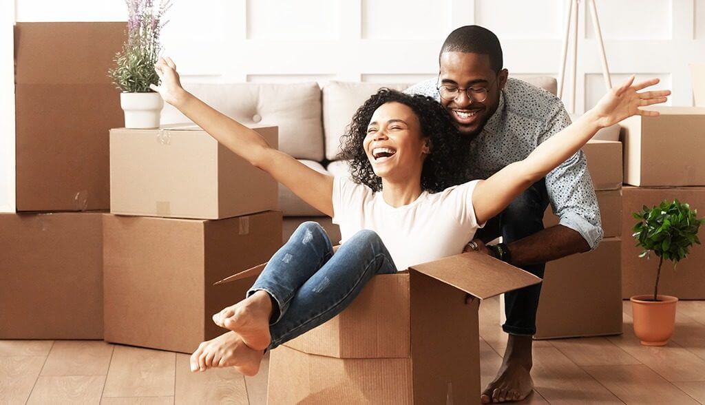 man pushing lady who is sitting in a moving box