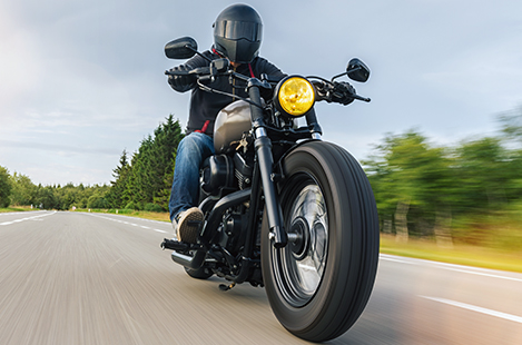 Closeup of motorcycle driving down road at sunset