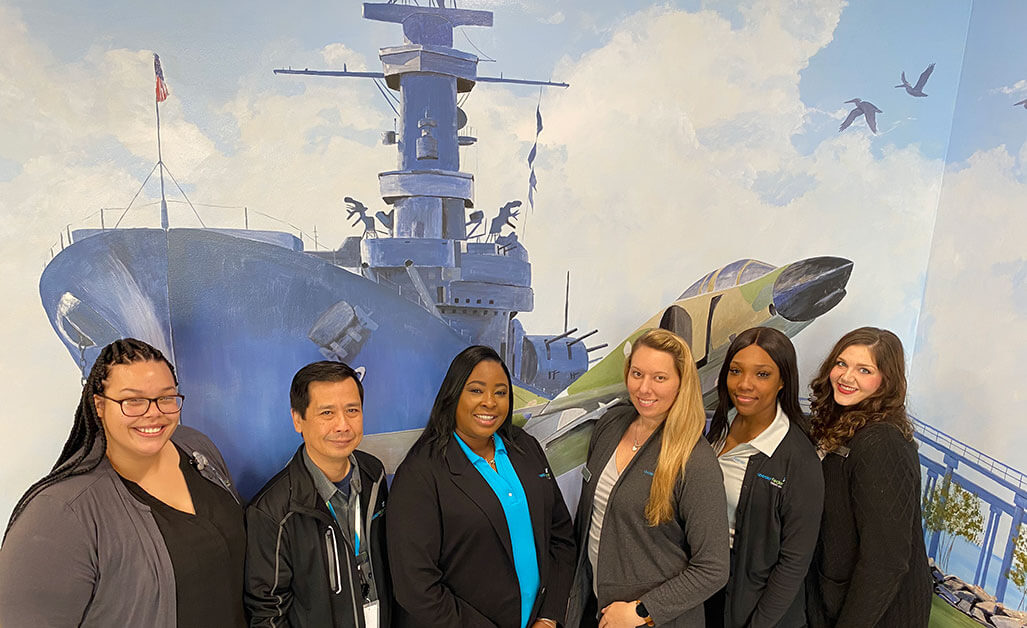 Mobile team members in front of mural of the battleship